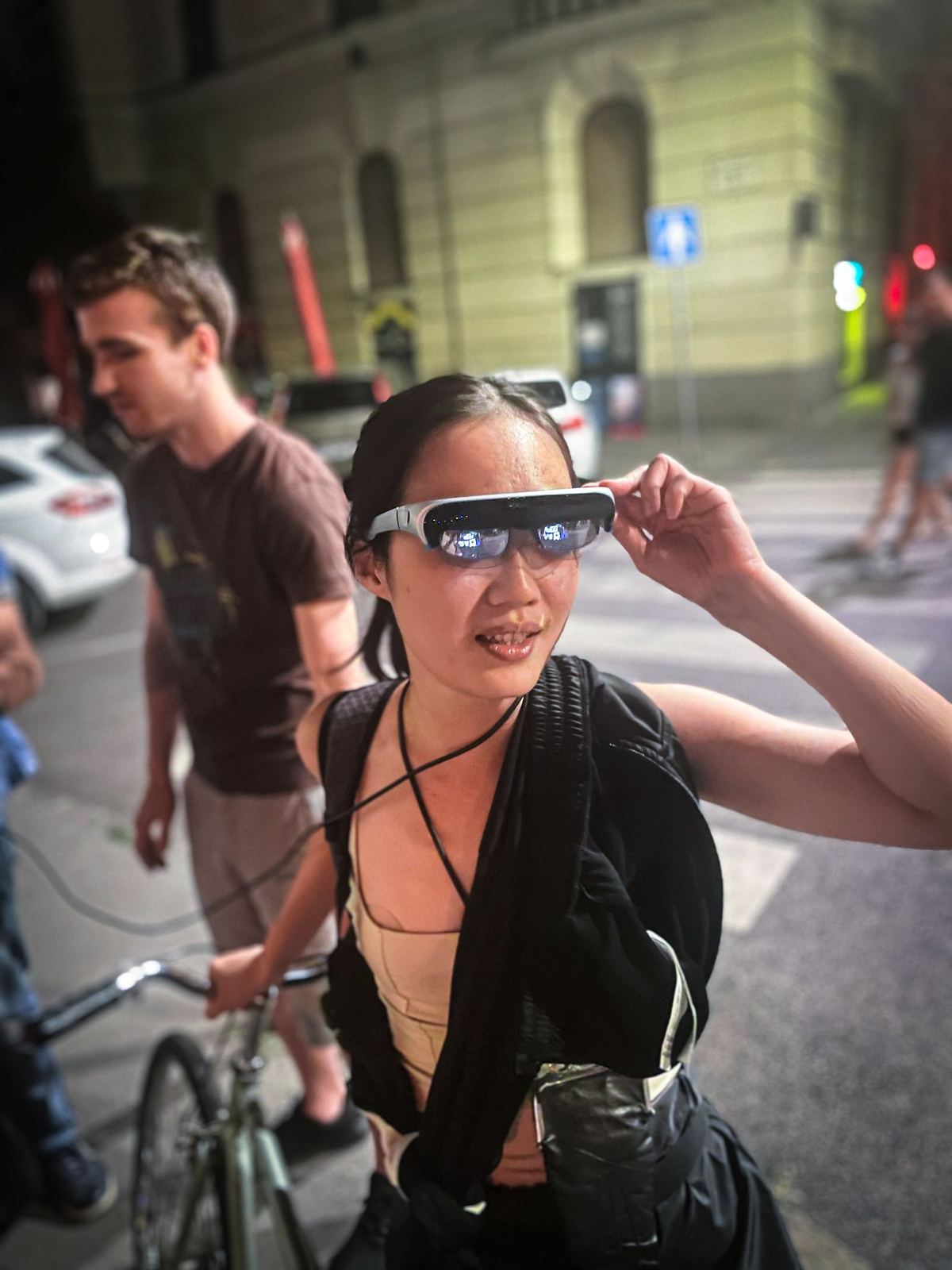 Az XR Budapest-találkozó egy résztvevője AR-szemüveget próbál ki egy esti városi utcán.